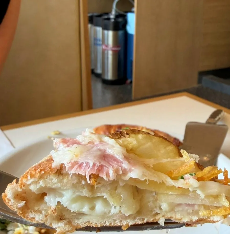 A slice of potato pizza topped with fried potato