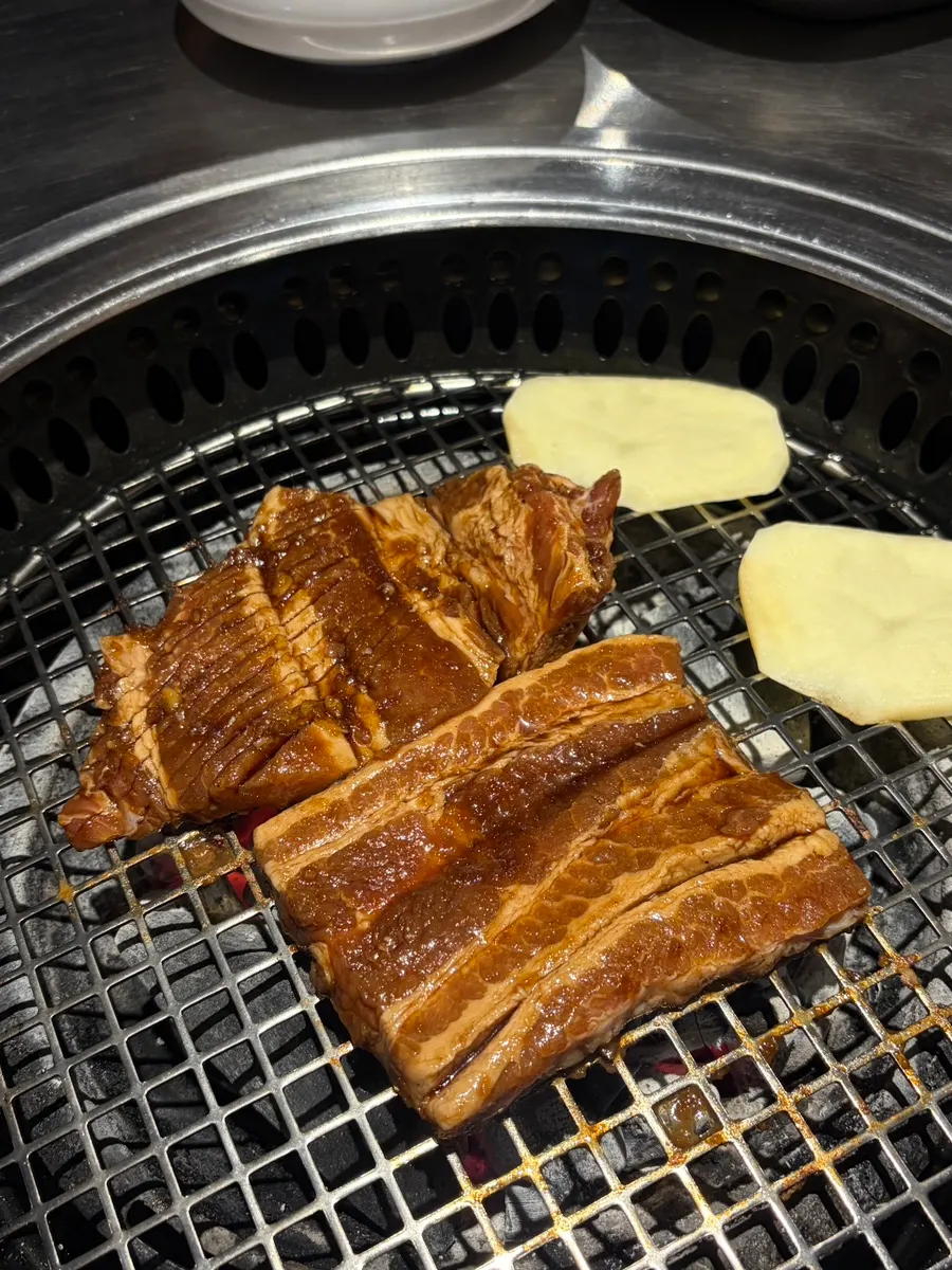 Marinated ribs grilling on charcoal with potatoes and king oyster mushrooms