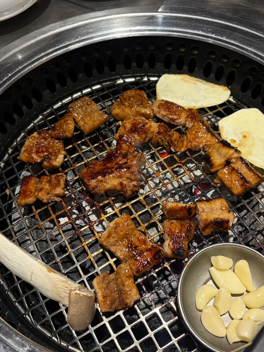 Charcoal grill with garlic cooking alongside the meat