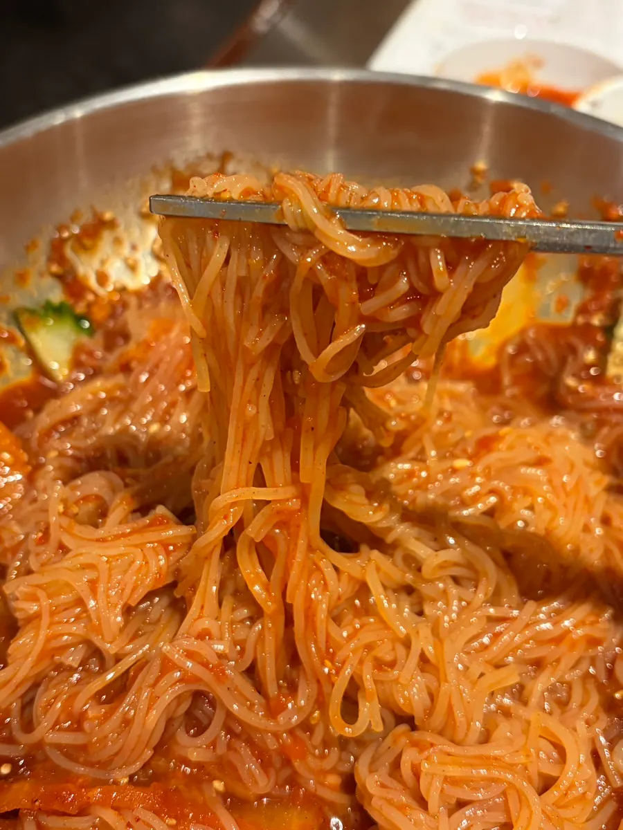 A bite of milmyeon noodles eaten together with marinated ribs