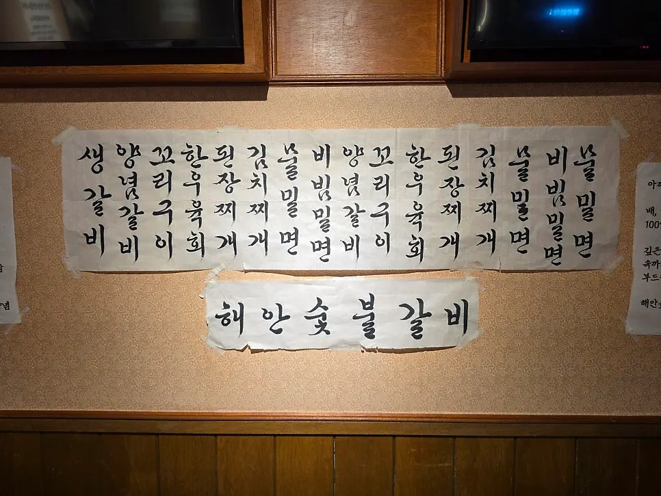 한지에 붓글씨로 적힌 해안숯불갈비 메뉴판