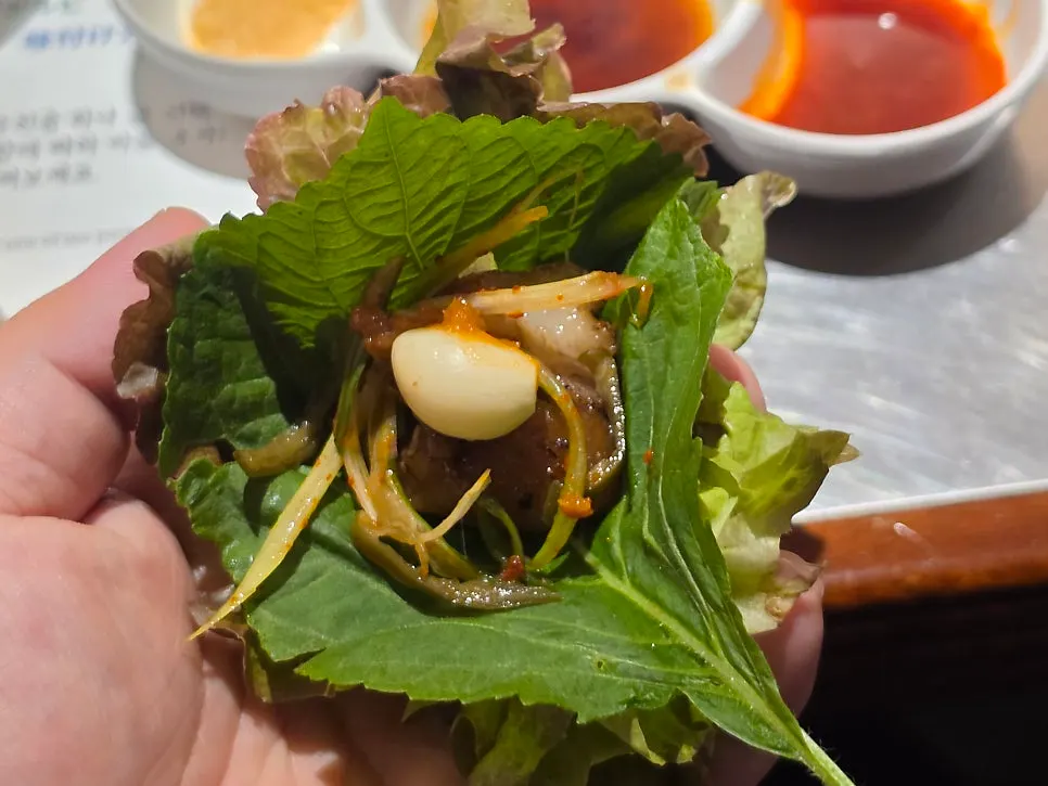 쌈야채에 파절임과 마늘을 올린 꼬리구이 쌈
