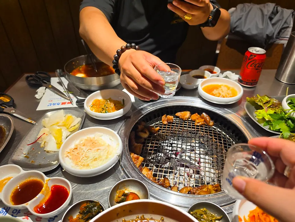 숯불 위에서 익어가는 꼬리구이와 술자리 테이블