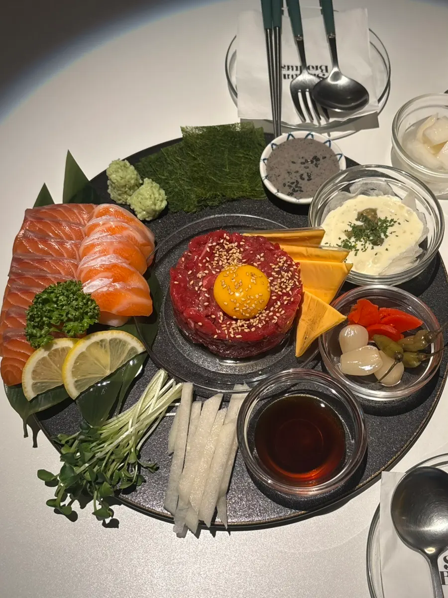 Beef tartare topped with egg yolk beside a thick 300g salmon plate