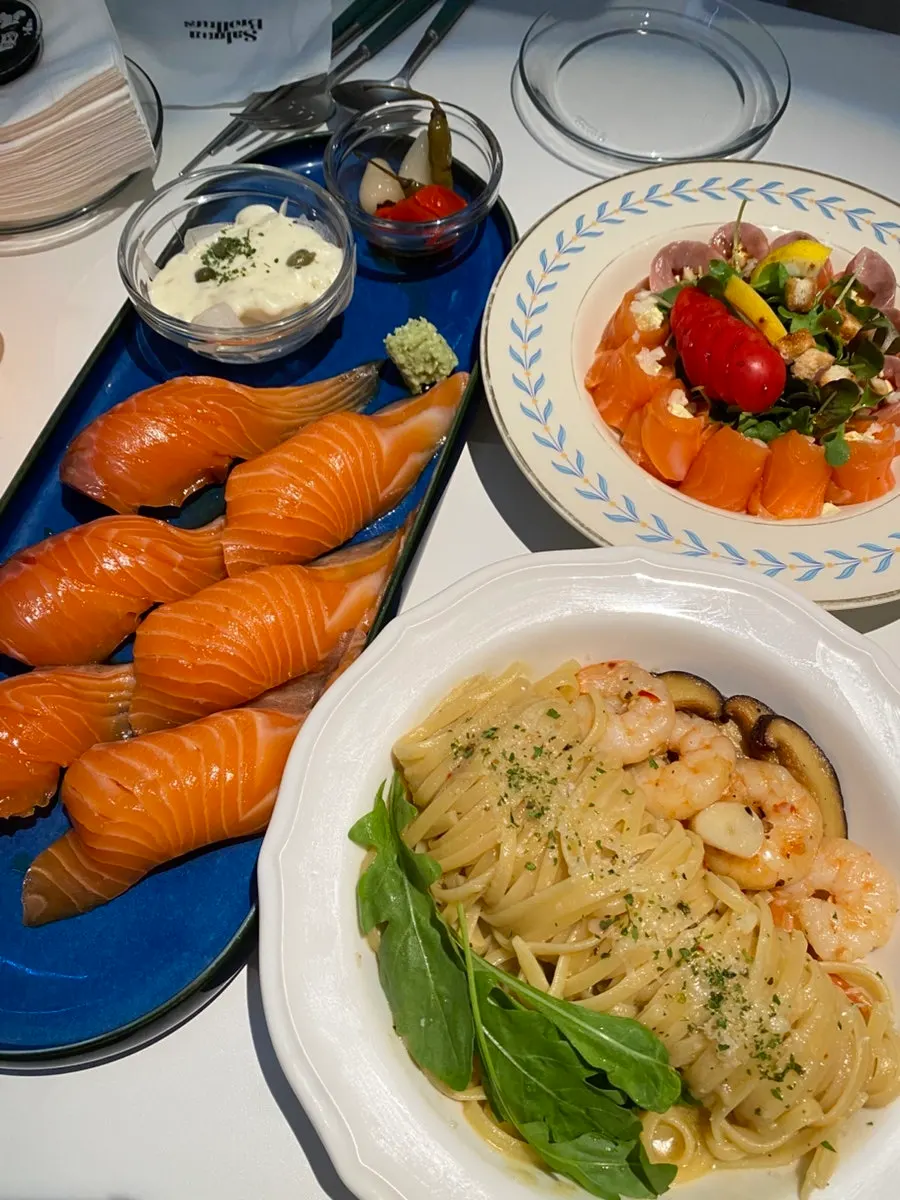 Table spread with raw salmon sushi and salmon cheese roll