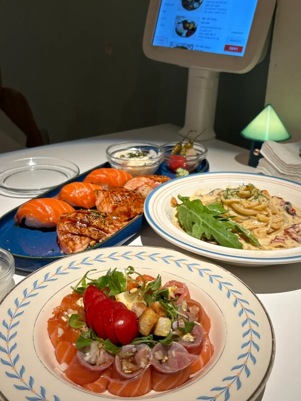 Table set with half-and-half sushi, cream cheese roll, and pasta