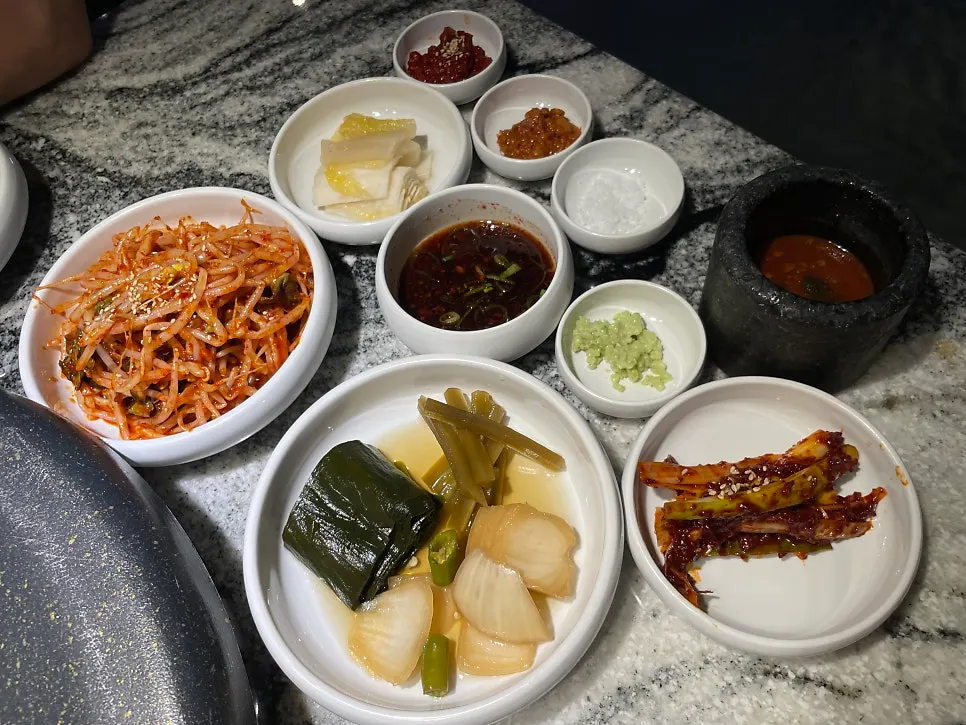 Table set with bean sprouts, green onion kimchi and myeoljeot side dishes