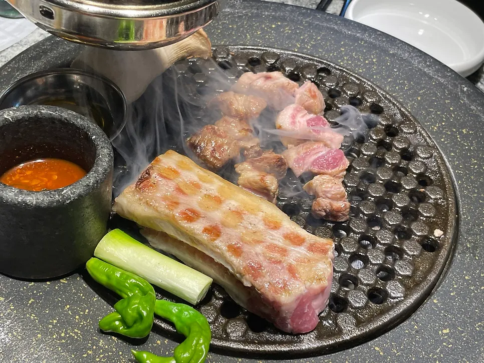 Pork belly and vegetables sizzling on the grill