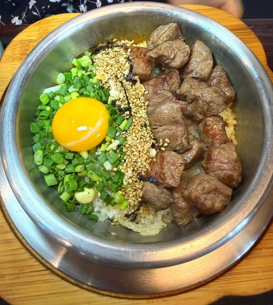Steak pot rice topped with egg yolk and scallions