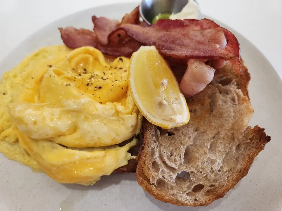 Toast topped with scrambled egg and bacon