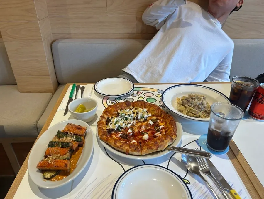 Table set with pizza, pasta, and grilled vegetables