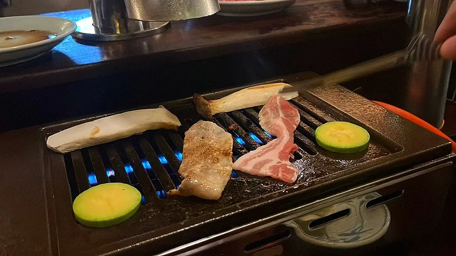 화로 위 고기와 밑반찬이 놓인 테이블