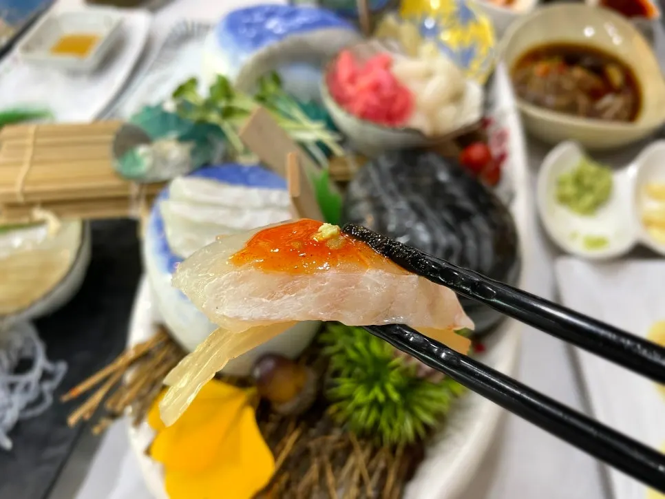 A piece of sashimi dipped in chojang and wasabi