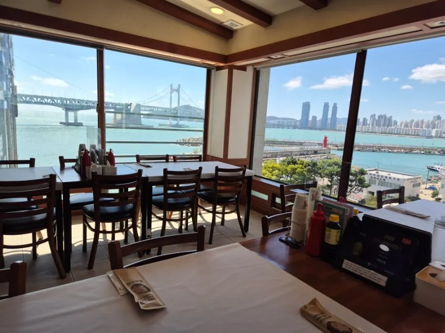 6th-floor interior tables at Gwanganda with the Gwangan Bridge sea view outside