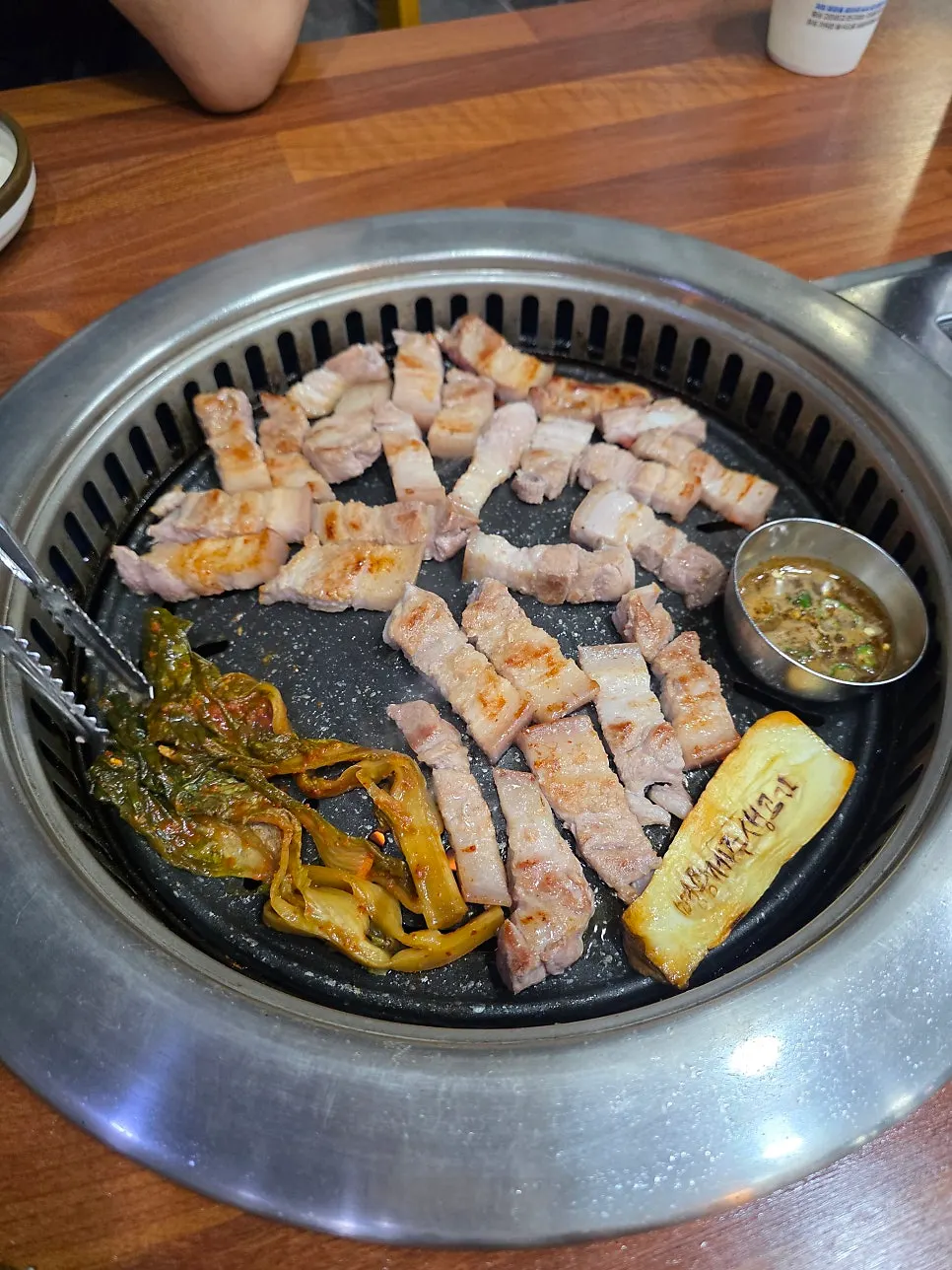 Three servings of thick pork belly cooking on the grill