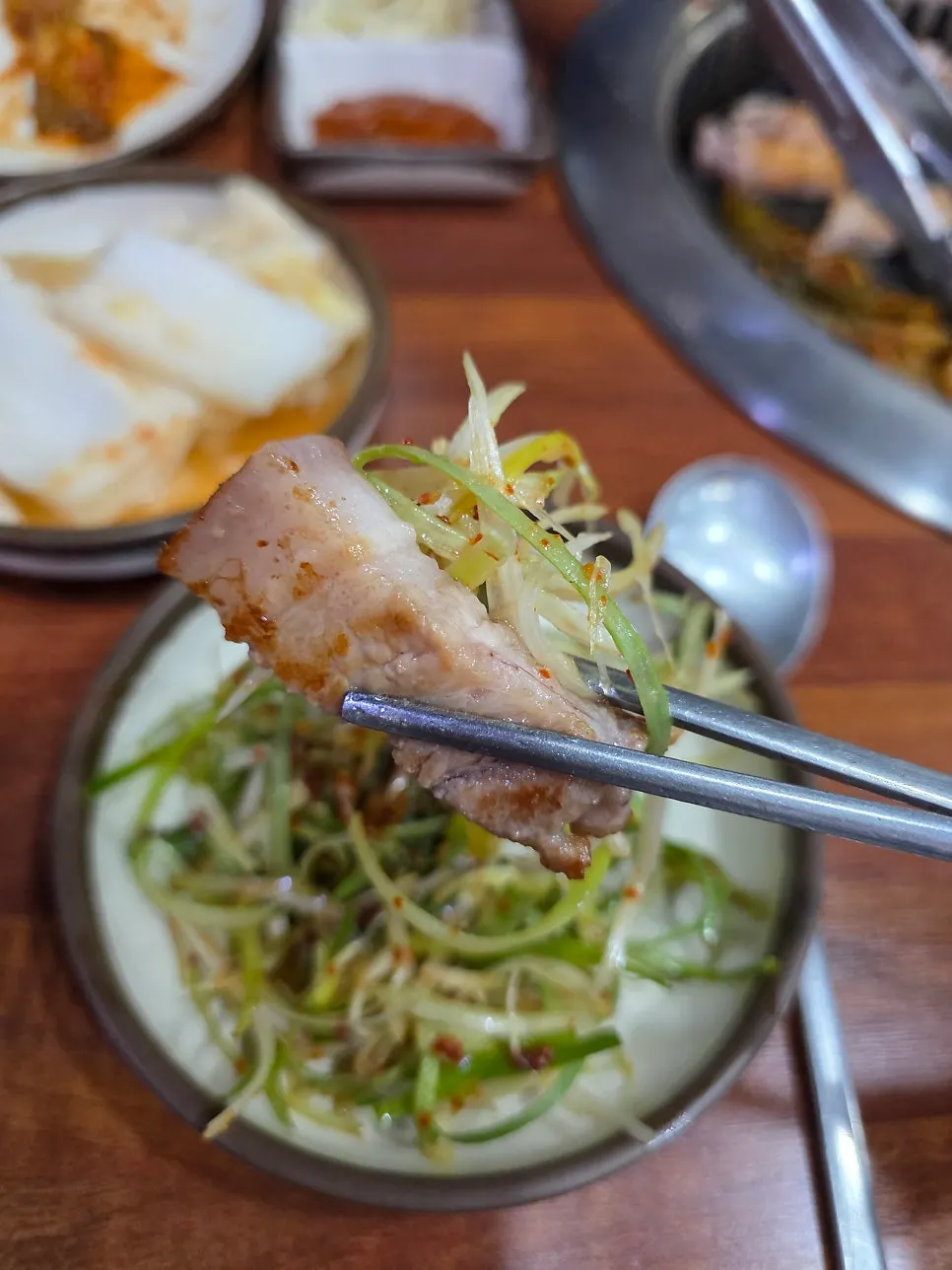 A piece of grilled pork belly being picked up