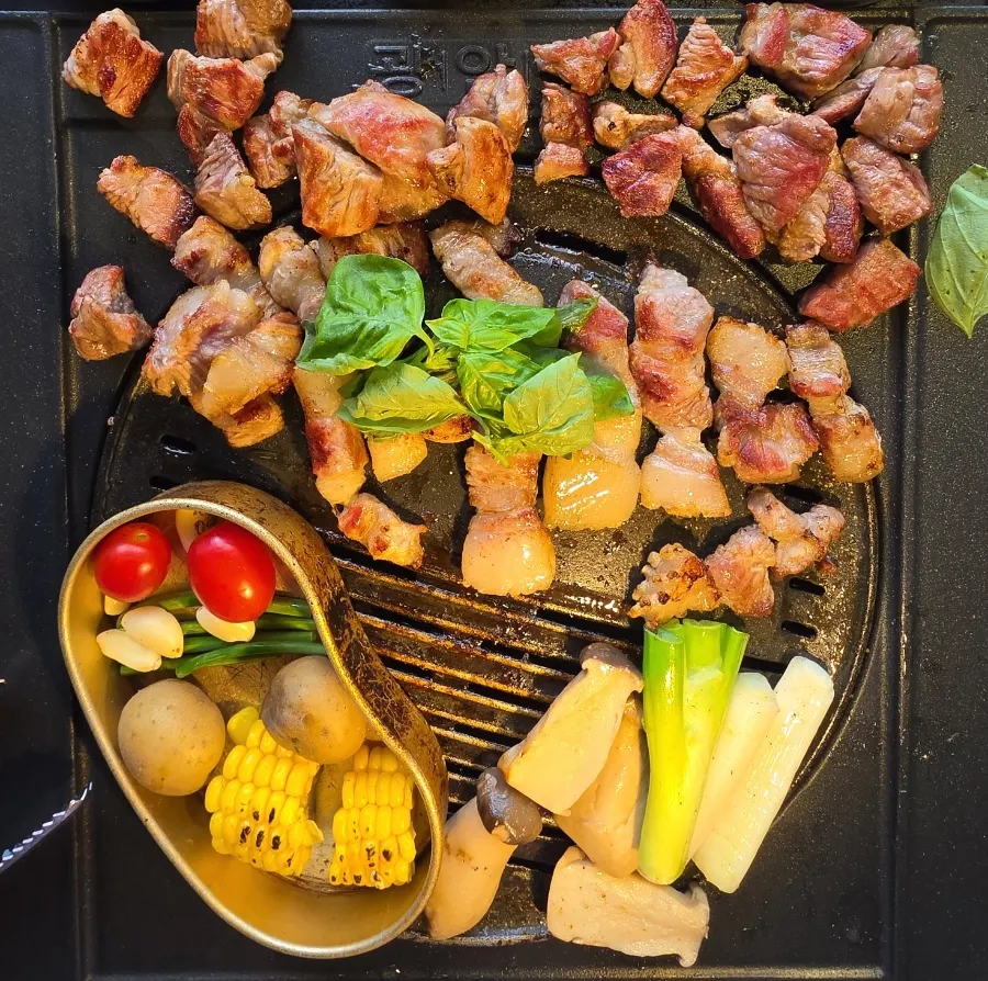 Thick cuts of aged pork belly grilling on the grill