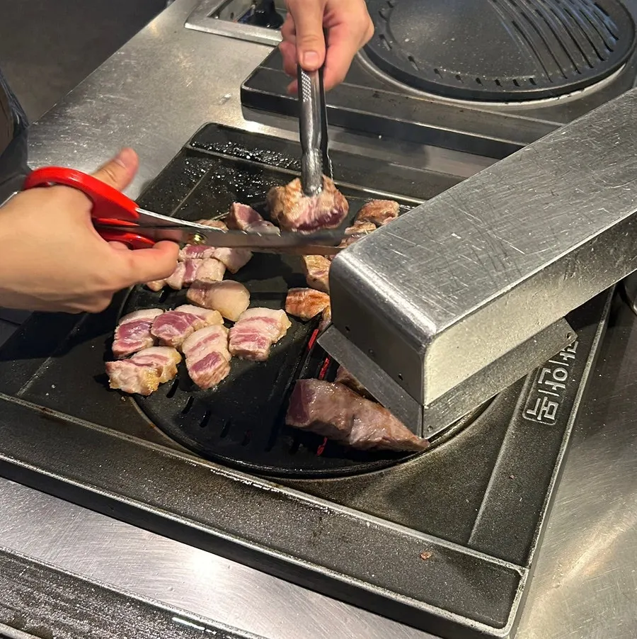 Staff member grilling meat on the tabletop grill