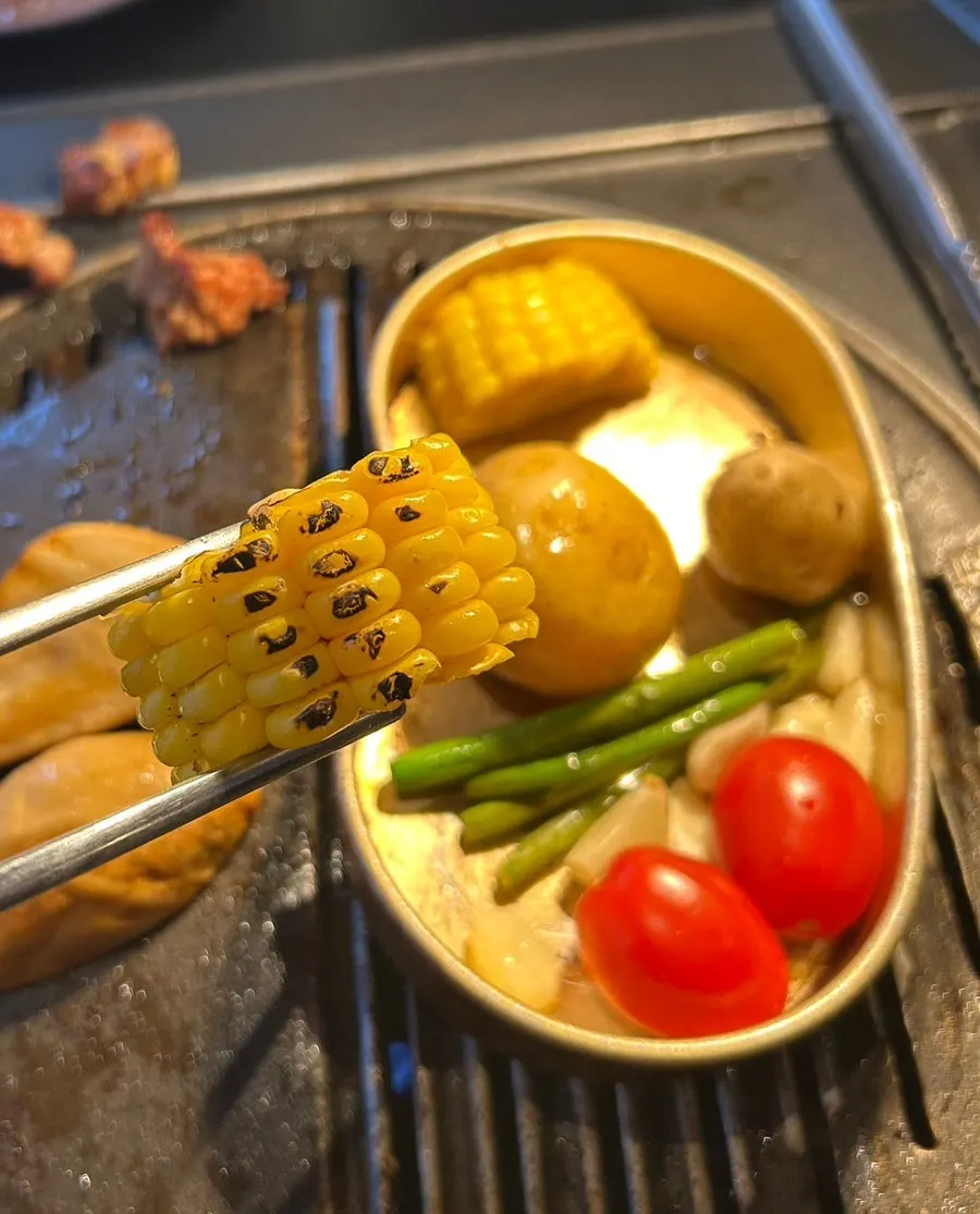 Butter-grilled vegetables and meat cooking on the grill