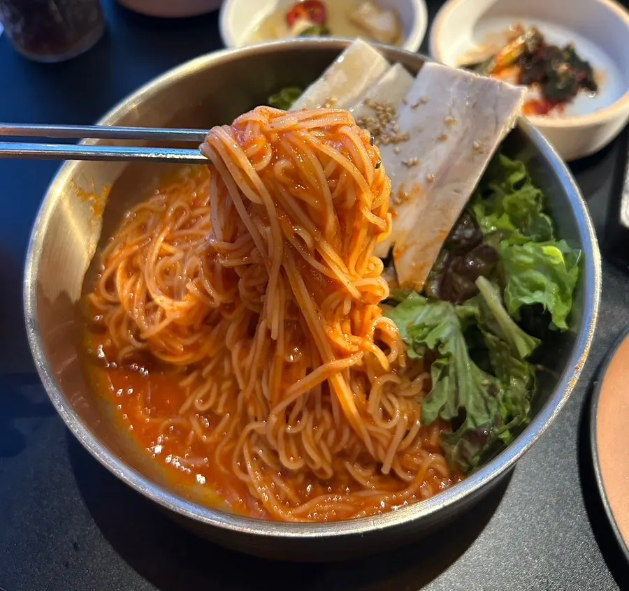A piece of meat placed on top of the bibim noodles