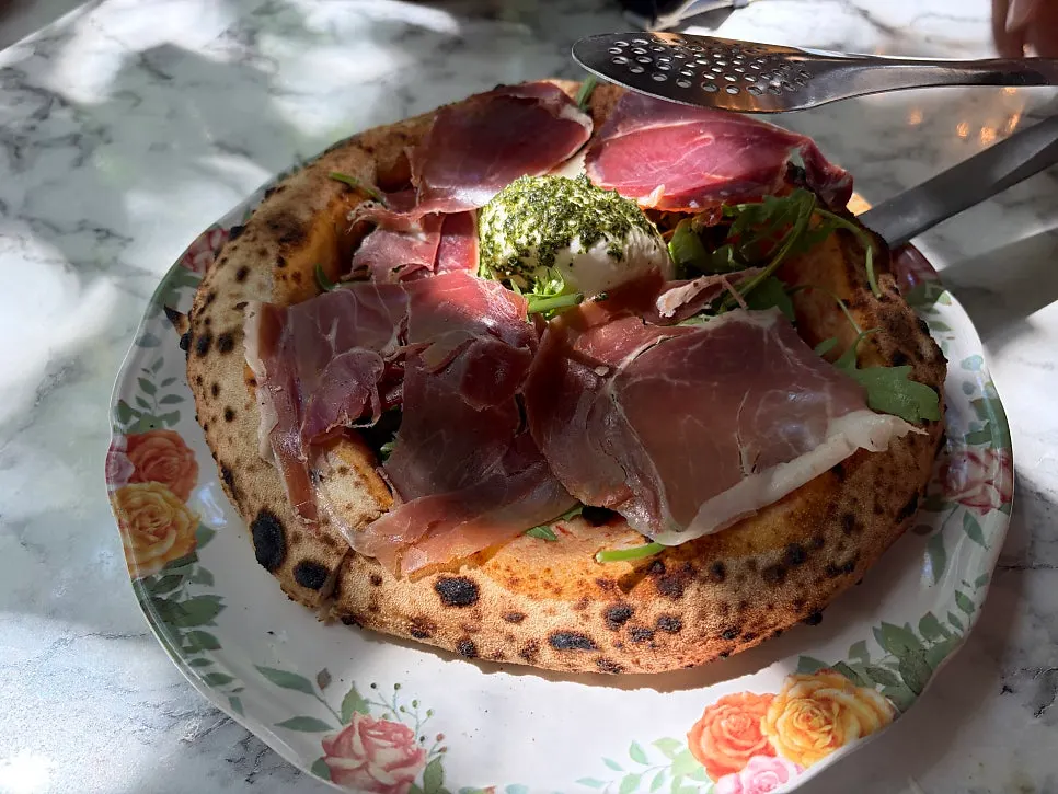 Close-up of the pizza topped with rocket and hamon
