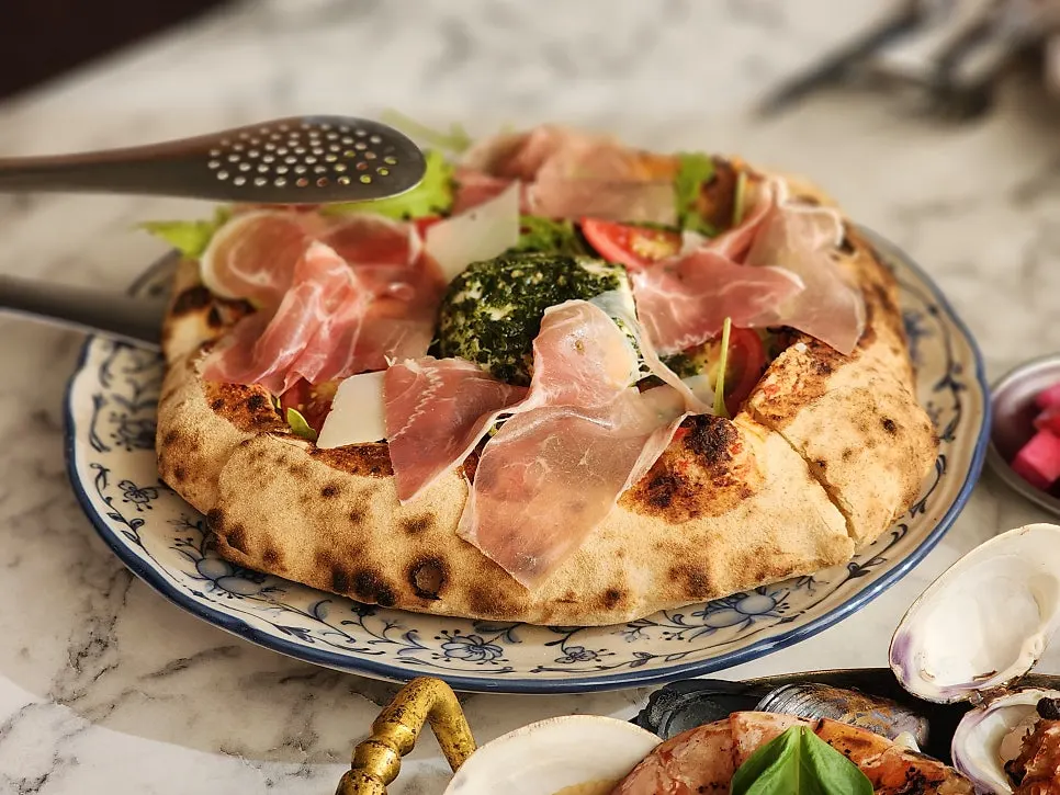 Table with the pasta and rocket ham pizza set out
