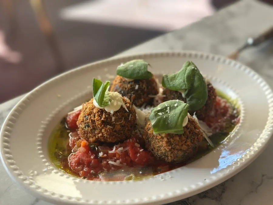 Squid ink arancini cut in half showing the rice inside