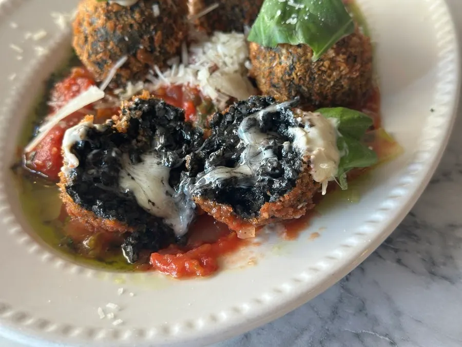 A single piece of squid ink arancini picked up