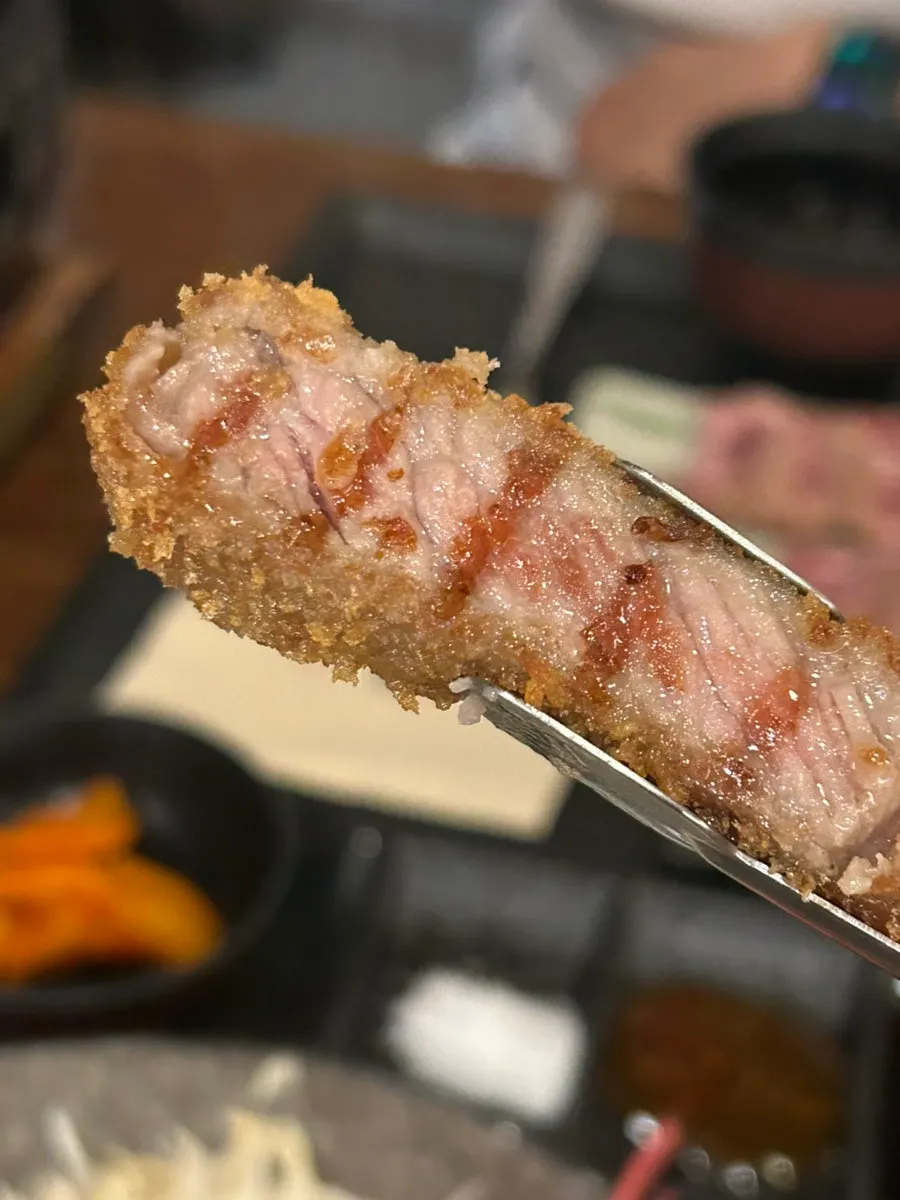 A piece of gyukatsu dipped in wasabi and sauce
