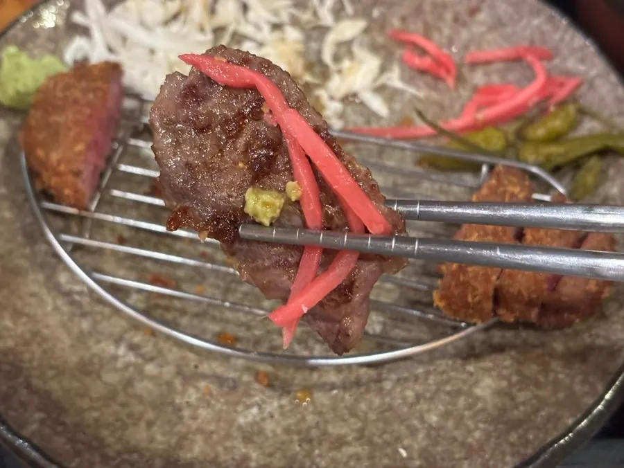 Chopsticks picking up a grilled piece of gyukatsu