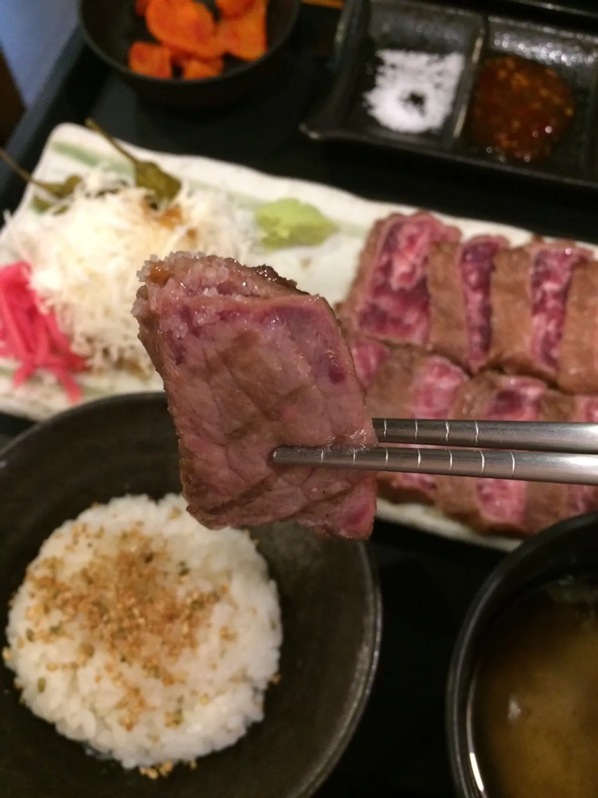 A tender piece of gyusteki meat picked up with chopsticks