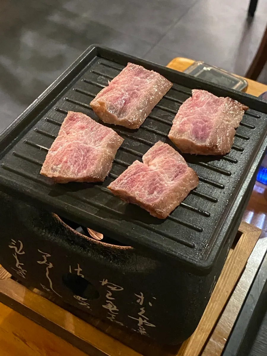테이블에 놓인 미니 화로에 고기 올리는 모습