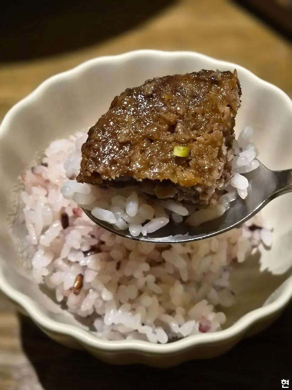 A piece of tteokgalbi with a spoonful of white rice