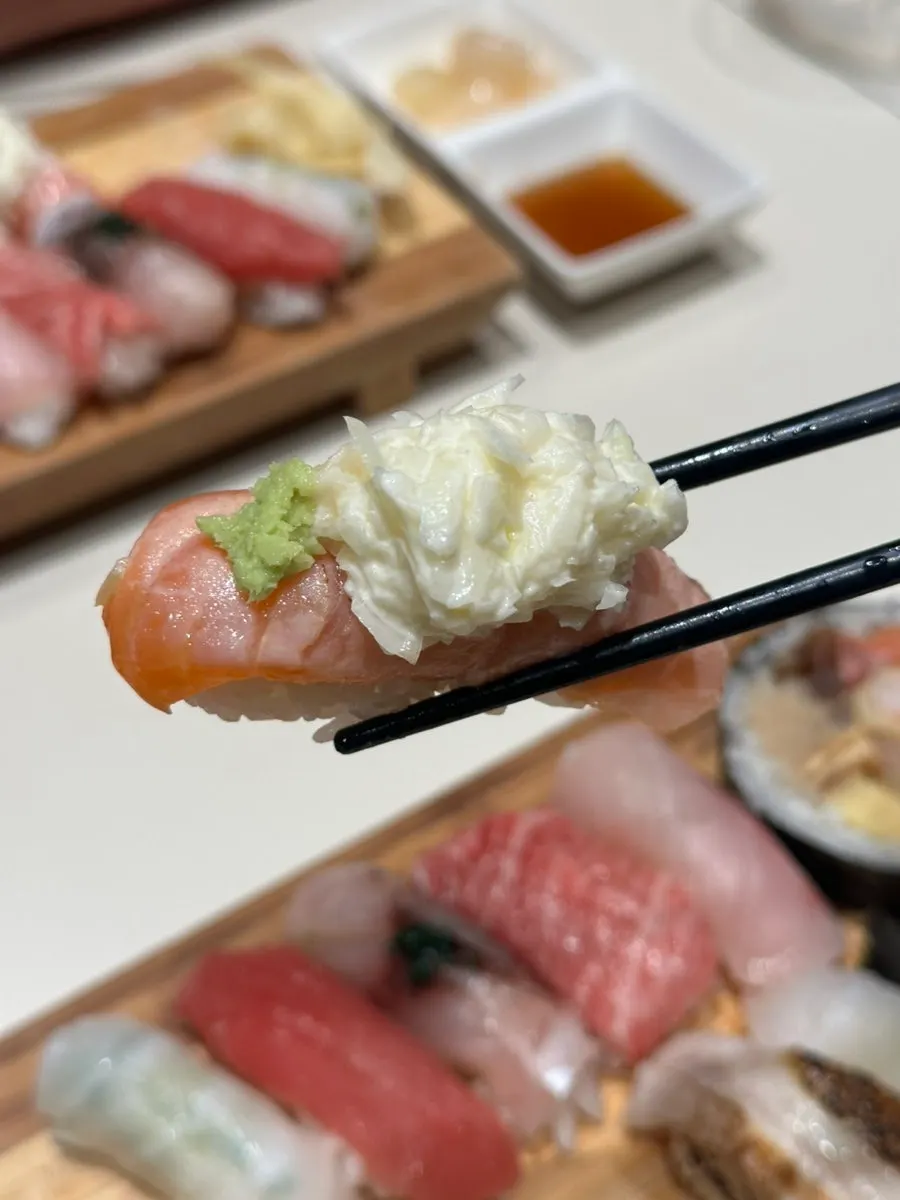 Seared salmon aburi sushi topped with onion garnish