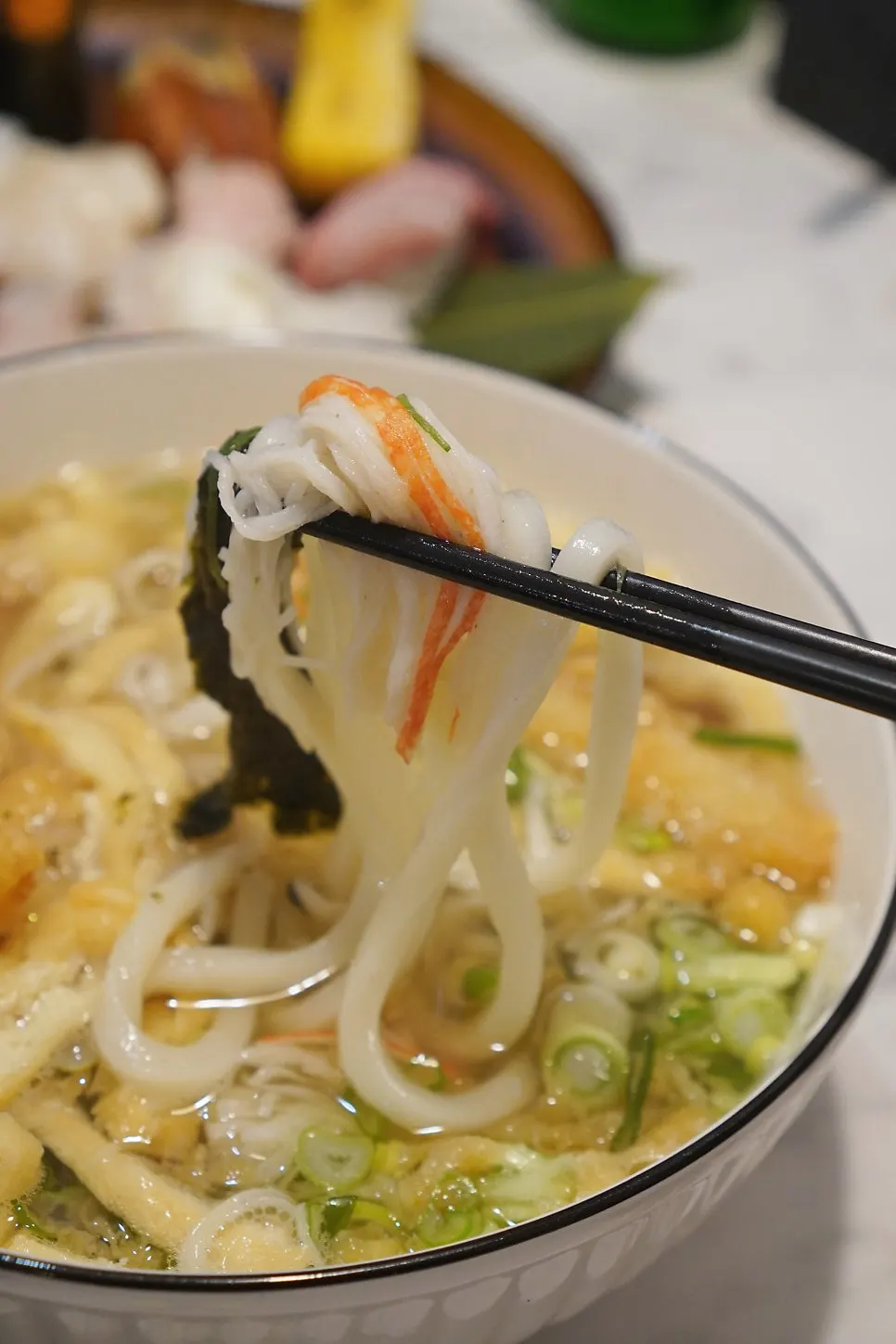A bowl of shrimp tempura udon topped with ingredients