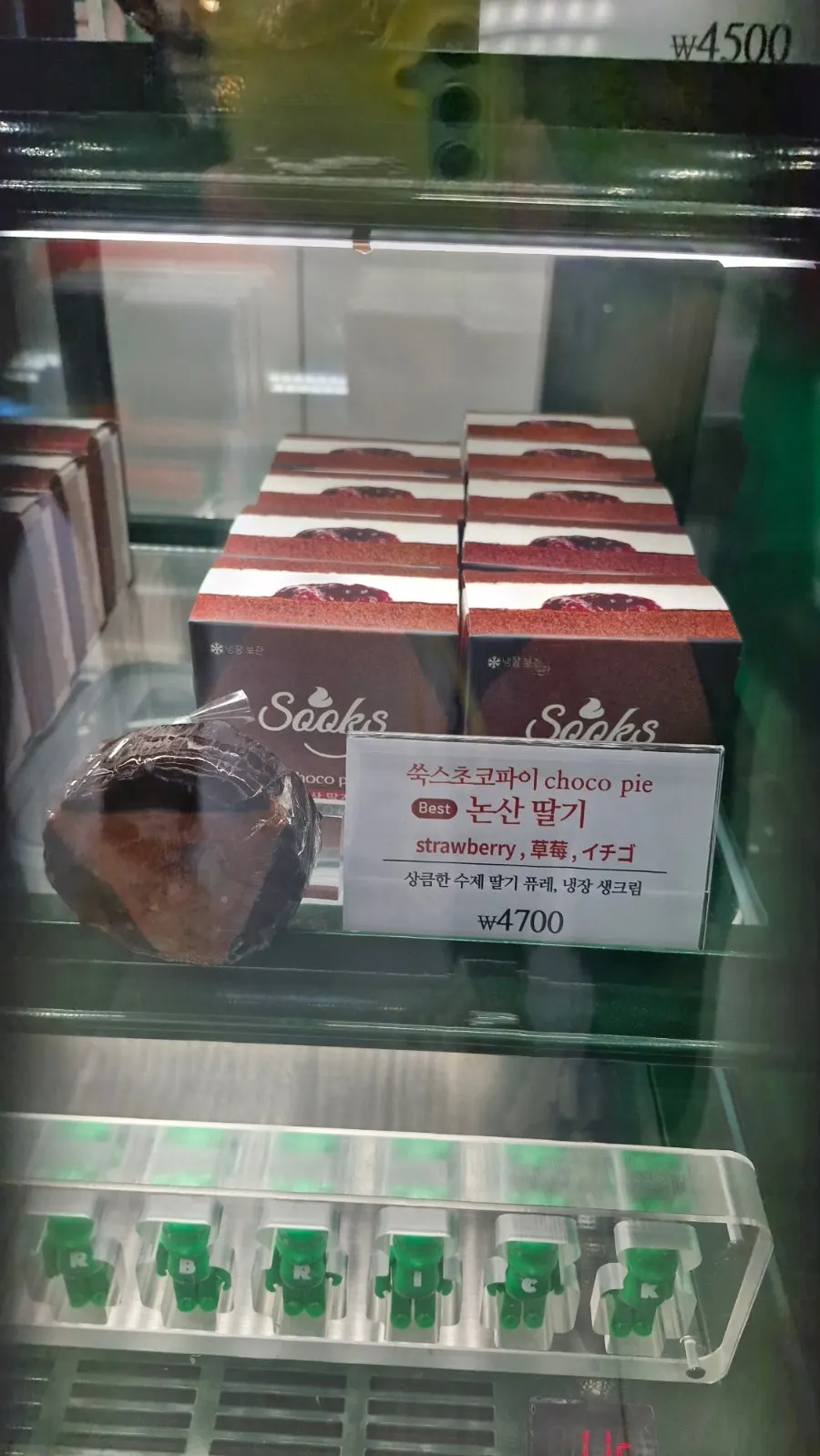 展示台上的绿色招牌购物袋与小熊瓶装饮料