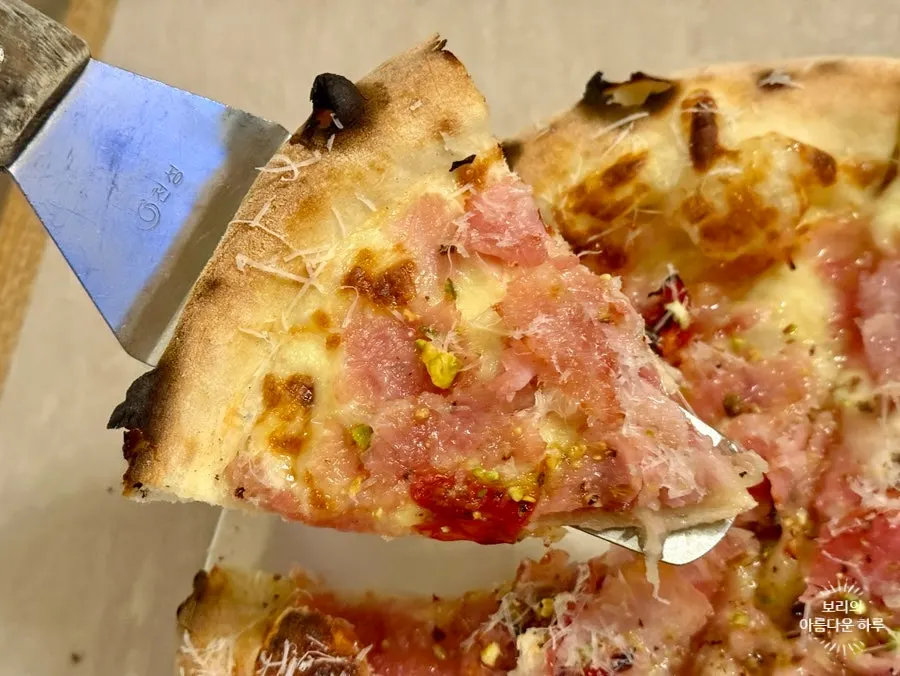 Slice of jambon pizza topped with honey and pistachios