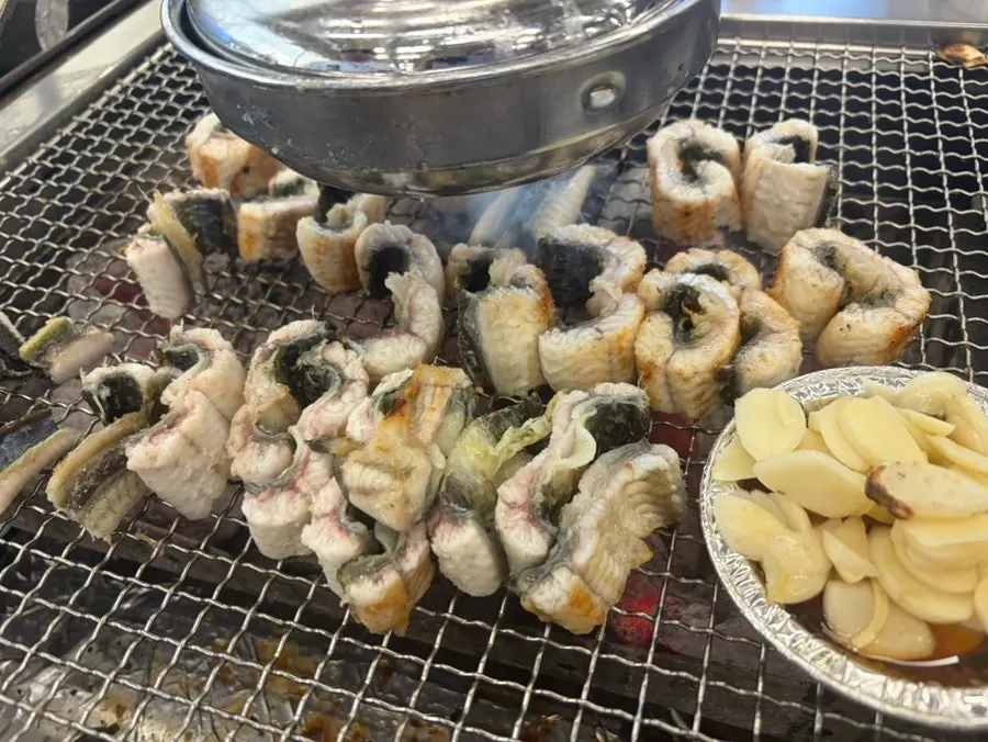 Charcoal-grilled eel being flipped back and forth