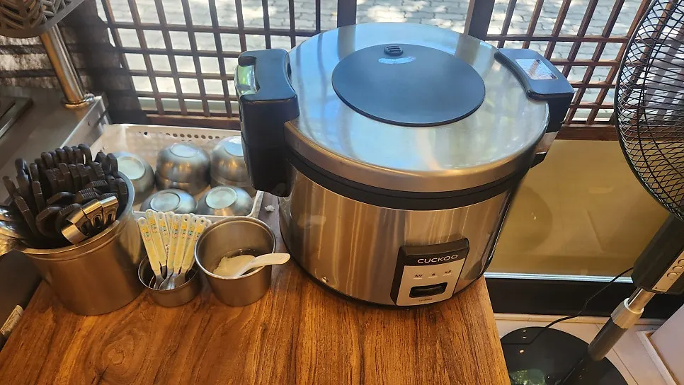放有黄萝卜、葱丝小菜和电饭煲的自助专区