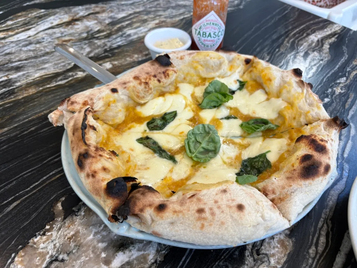 A slice of wood-fired pizza served with dipping sauce