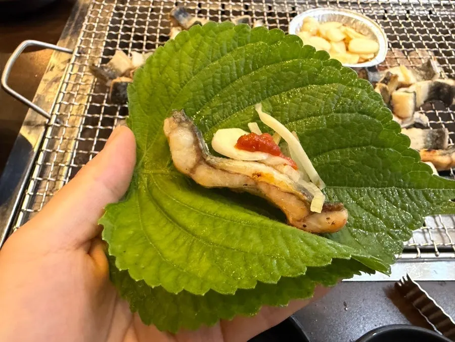A piece of eel eaten wrapped with lettuce and vegetables