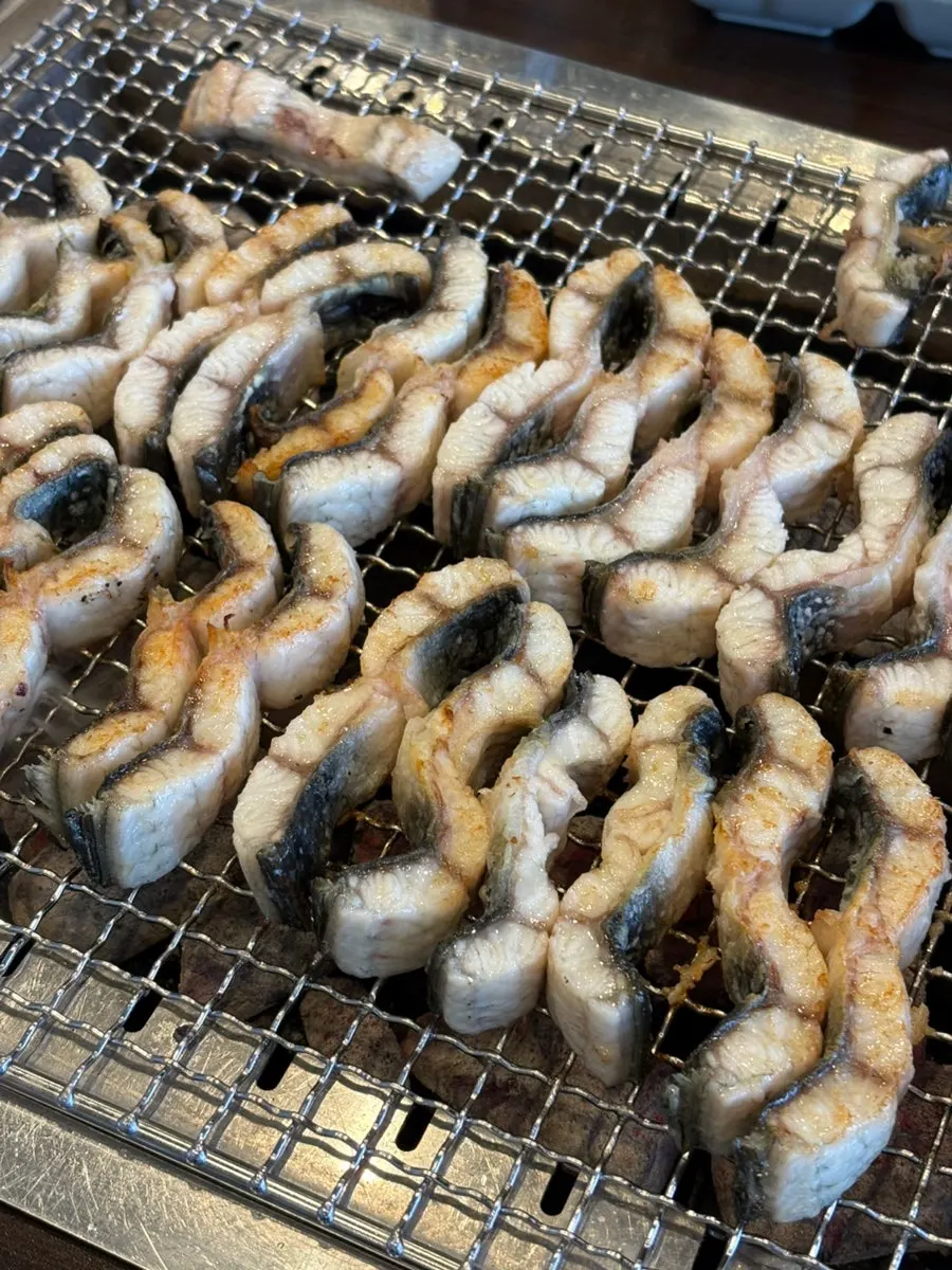 Eel turning golden brown over strong charcoal heat