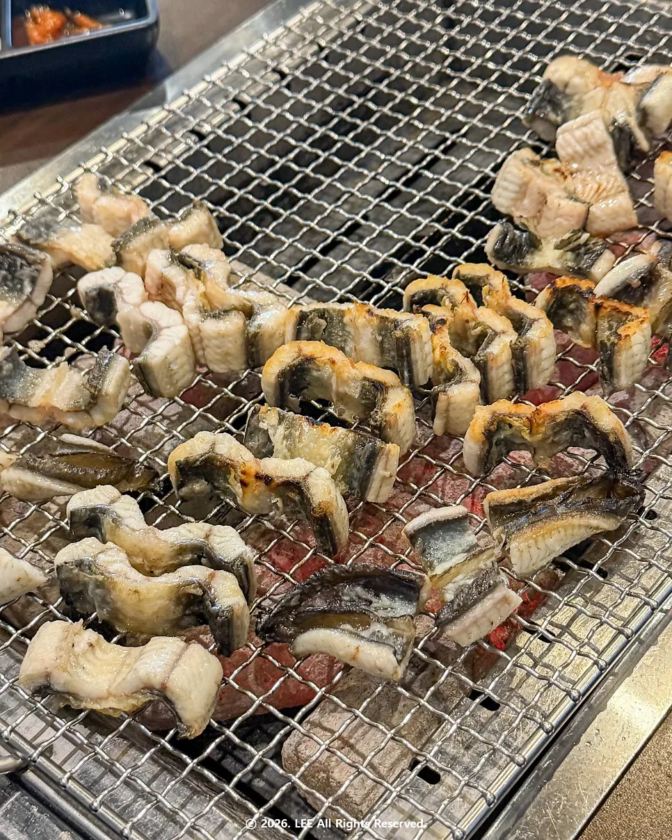 Pre-grilled eel cooking over charcoal