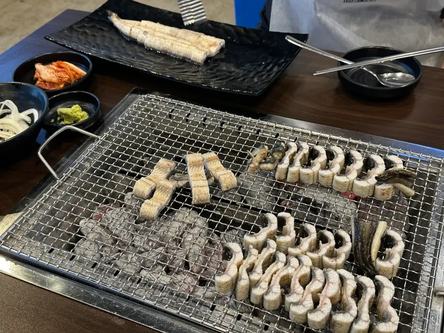 Pre-grilled eel standing upright over the charcoal