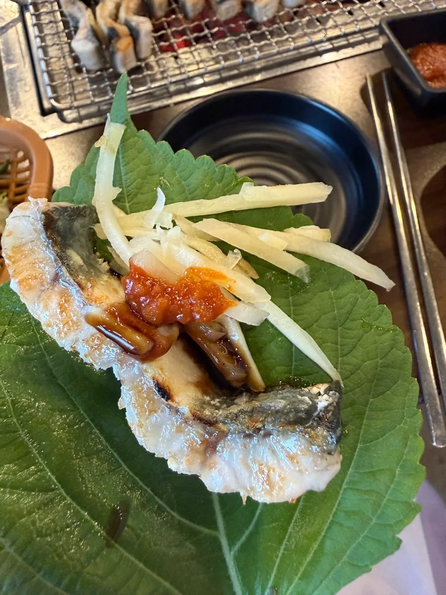 A grilled piece of eel picked up with chopsticks