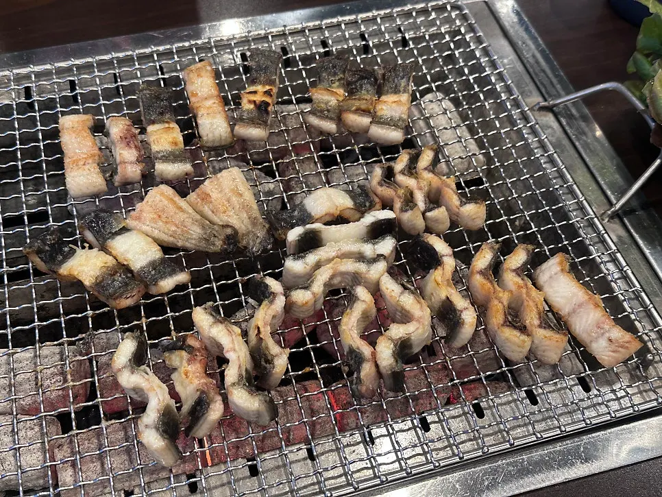 Pre-seared eel grilling golden brown over charcoal