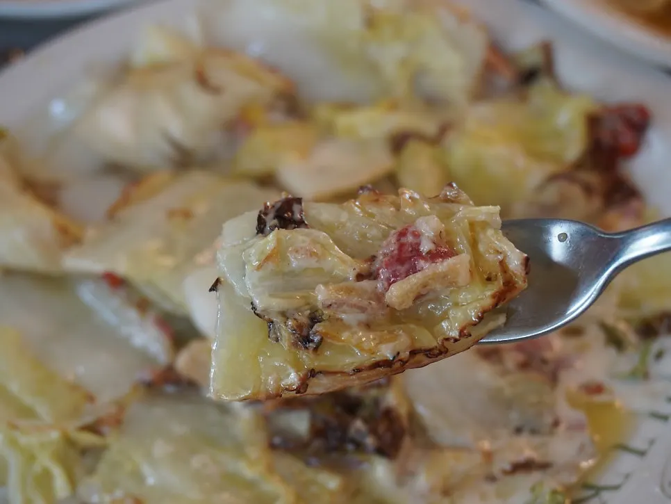 Napa cabbage Caesar salad topped with bacon chips and cheese