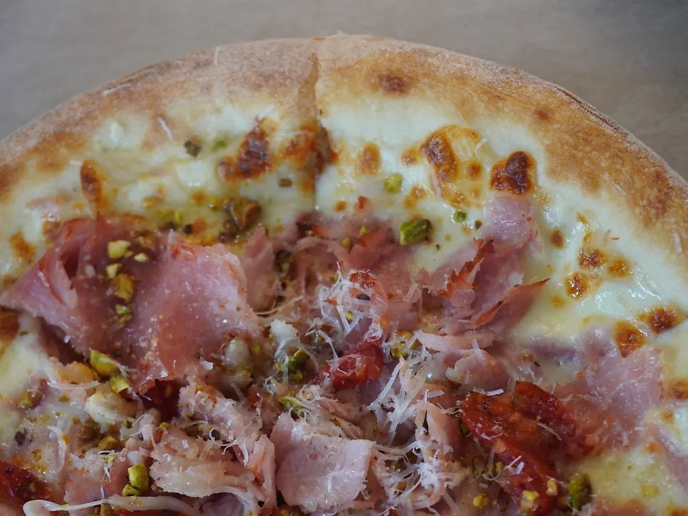 Jambon pizza topped with honey and pistachios