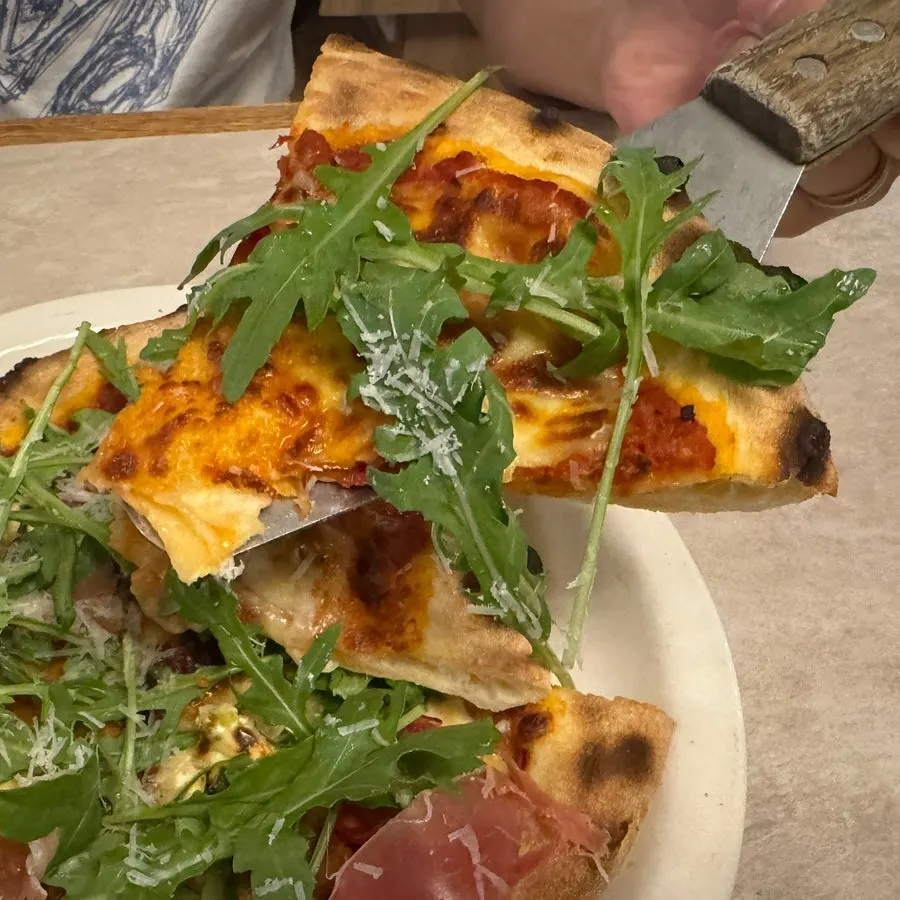 Pizza topped with arugula and prosciutto