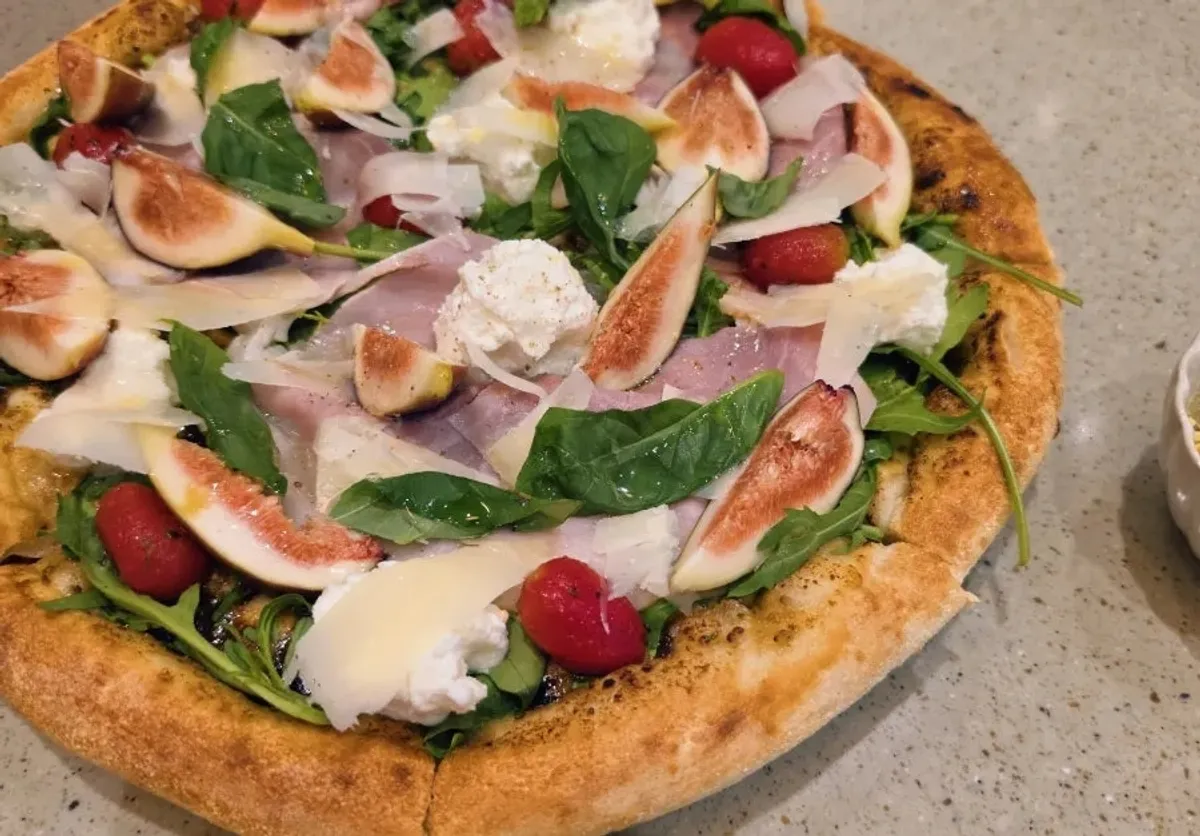 A slice of Fig Fresco pizza topped with pistachio